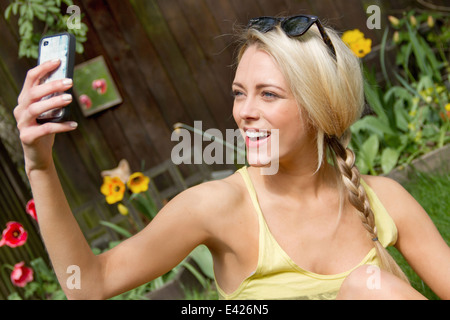 Giovane donna in giardino tenuto selfie sullo smartphone Foto Stock