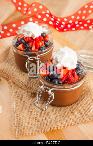Mousse al cioccolato in contenitori di carino e rabboccato con mirtilli e fragole con panna montata. Vegane. Foto Stock