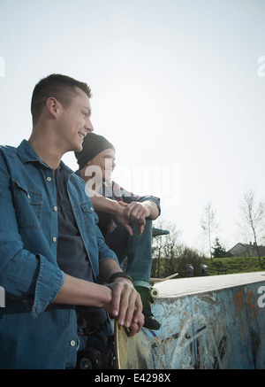 Giovani uomini seduti insieme a skatepark Foto Stock