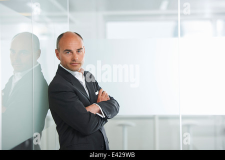 Imprenditore appoggiata contro la parete riflettente Foto Stock