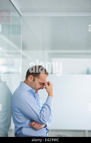 Imprenditore contemplando contro la parete riflettente Foto Stock