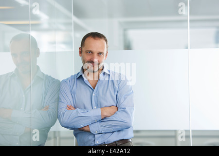 Imprenditore appoggiata contro la parete riflettente Foto Stock