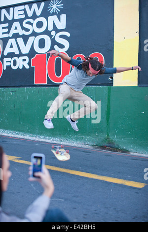 Giovani maschi adulti fotografato sullo smartphone facendo lo skateboard trick Foto Stock