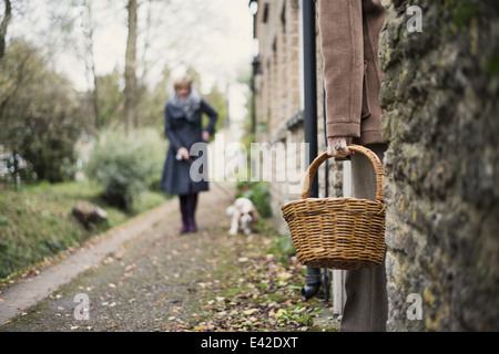 Senior woman standing in porta a basso angolo di visione, in attesa di donna matura, cane a piedi Foto Stock