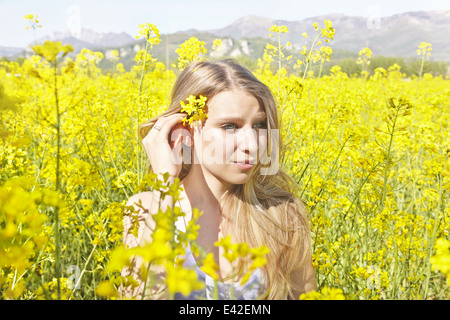 Giovane donna con fiore giallo nei capelli, ritratto Foto Stock