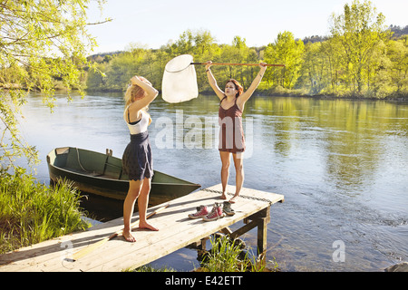 Giovani donne in piedi sul molo, una holding rete da pesca Foto Stock