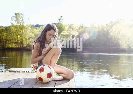 Ragazza con tavoletta digitale sul molo Foto Stock