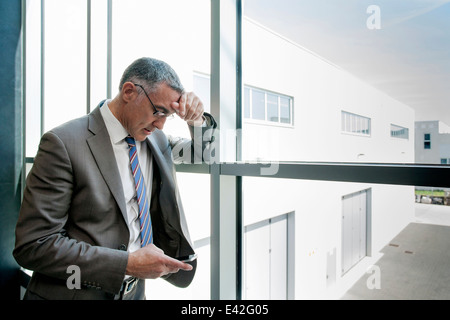 Imprenditore utilizza lo smartphone da parete in vetro Foto Stock