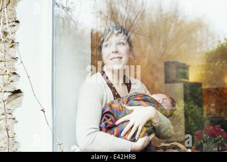 Madre con bambino guardando fuori della finestra Foto Stock