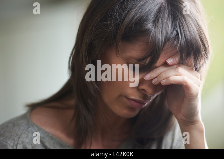 Donna matura con testa in mani Foto Stock