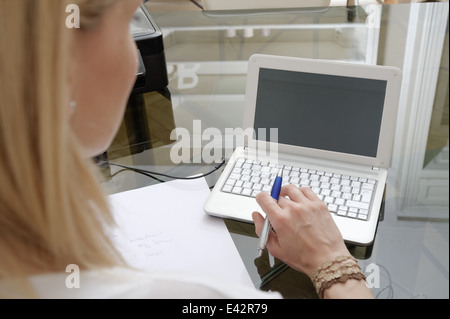 Tagliato in prossimità della giovane donna digitazione sul portatile a casa Foto Stock