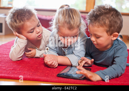 Due ragazzi e una ragazza utilizzando digitale compressa in una scuola materna Foto Stock