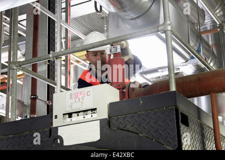 Tecnico sul marciapiede facendo controllare nella stazione di alimentazione Foto Stock