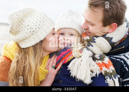 Metà dei genitori adulti baciare la loro figlia sulla guancia a costa Foto Stock