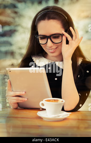 Giovane donna con gli occhiali e la pastiglia di caffè Foto Stock