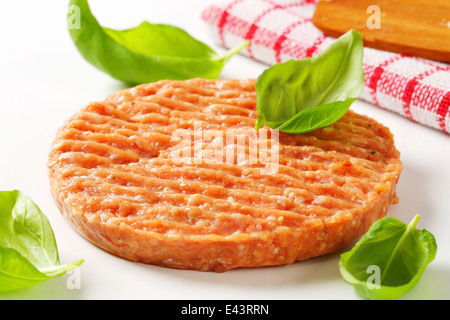 Materie burger patty con foglie di basilico fresco Foto Stock