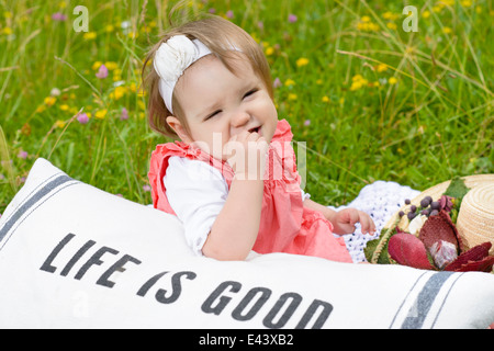 Carino Baby girl relax nella natura su un cuscino Foto Stock