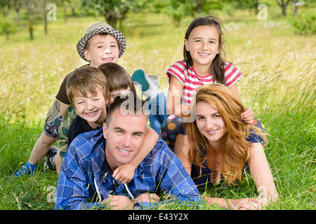 La famiglia felice godendo di una soleggiata giornata estiva in un frutteto Foto Stock