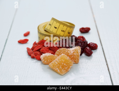 Bacche di Goji, cranberry, zenzero candito e nastro di misurazione, il concetto di salute Foto Stock