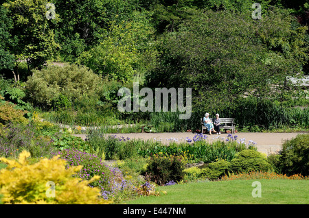 Due anziane signore seduto sul banco in giardini formali Foto Stock