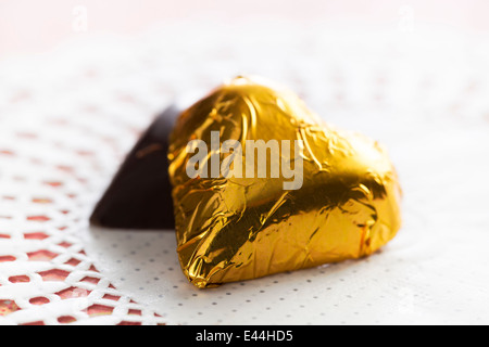 Due cuori, uno avvolto in foglia d'oro, uno nascosto. Foto Stock