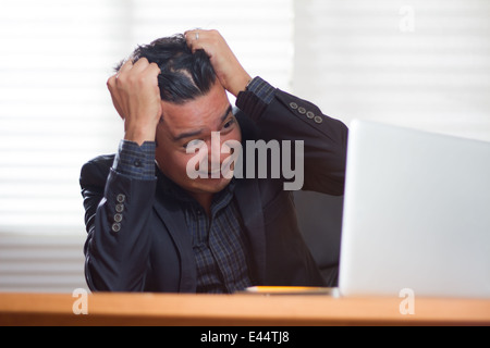 Un giovane dirigente è davvero disperata guardando al suo computer portatile Foto Stock