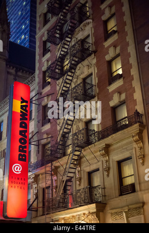 Edificio con illuminato in rosso segno e fire sfugge su Broadway, Manhattan, New York City. Foto Stock