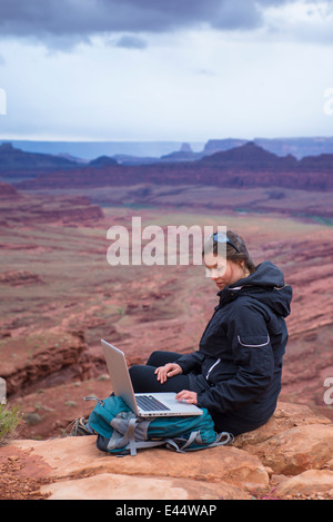 Ragazza escursionista sulla cima della montagna con il suo computer portatile Foto Stock