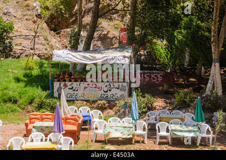Patio in plastica tavoli, sedie e ombrelloni presso i ristoranti sulle rive del fiume Ourika, Ourika Valley, Atlante, Marocco Foto Stock