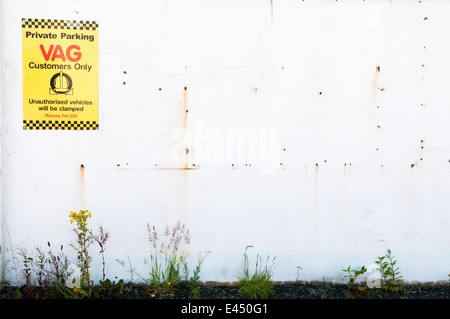 Segno sulla parete di un avvertimento che il parcheggio non autorizzato si tradurrà in veicoli essendo fissato ad un VAG centro di servizio Foto Stock