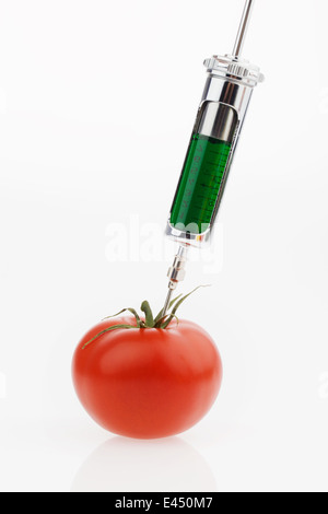 In un pomodoro, un liquido verde viene iniettato. Foto simbolico per i pomodori genetica. Foto Stock