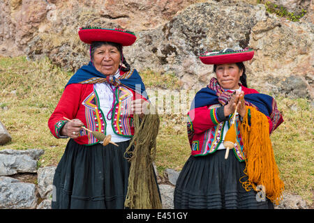 Due donne anziane indossare cappelli, gli Indiani Quechua, in abito tradizionale, la filatura della lana di legno di mandrini, Cinchero Foto Stock
