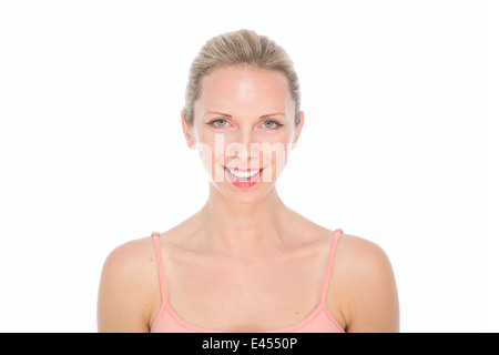 Attraente giovane donna bionda in rosa Vest alto con legati i capelli dal viso e trucco naturale sorridere con denti bianchi Foto Stock