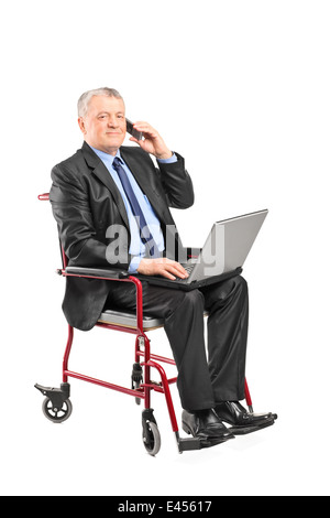 Imprenditore maturo lavorando sul computer portatile in una sedia a rotelle Foto Stock