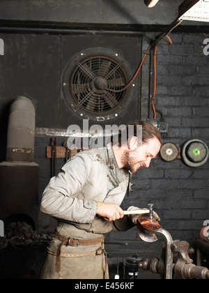 Fabbro martellare il rame in officina Foto Stock