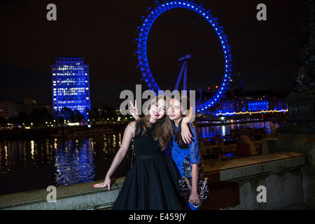 Ritratto di due amici di sesso femminile in posa con occhio di Londra di notte, Londra, Regno Unito Foto Stock