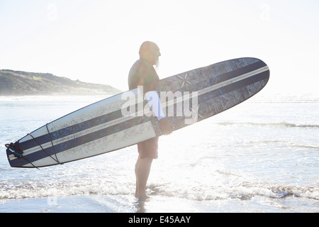 Maschio maturo surfer guardando il mare dalla spiaggia Foto Stock