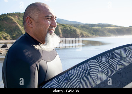 Maschio maturo del surfista con la tavola da surf a guardare il mare Foto Stock