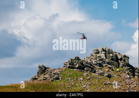 Aria di mare Salvataggio in elicottero sopra la testa Gurnards in Cornovaglia, hovering mentre sono in esercizio. La pratica di manovre per il soccorso di persone. Foto Stock