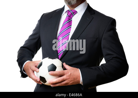 Business man in abito scuro e cravatta trattiene un pallone da calcio Foto Stock