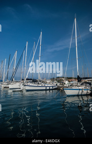 Yacht di lusso in blu e bianco ormeggiato a Saint Tropez su una bella giornata di sole e sotto un cielo blu con wispy blue clouds. Foto Stock