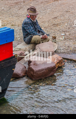 Un uomo e il fiume traghetti attraverso lo stretto di Tiquina, Bolivia prendere automobili, camion, autobus e moto attraverso il fiume. Foto Stock