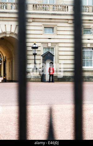Regina della Guardia sentry sul dazio a Buckingham Palace, London, vista dall'esterno il palazzo recinzione, Inghilterra Foto Stock