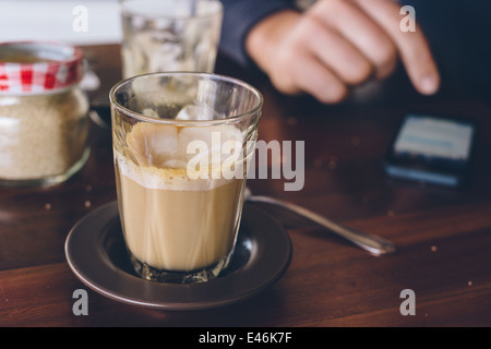 Un uomo con il suo telefono cellulare mentre in un cafe Foto Stock