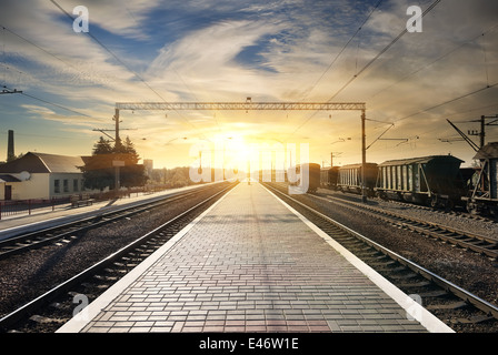 Carro merci sulla stazione al tramonto con le nuvole Foto Stock