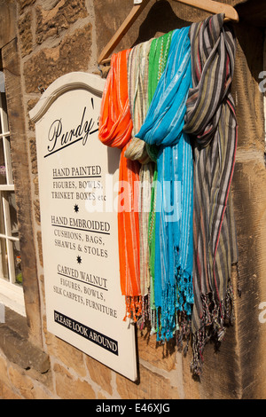 Regno Unito, Derbyshire, Peak District, Bakewell, acqua Street, colorate sciarpe sul display al di fuori del negozio di abbigliamento Foto Stock