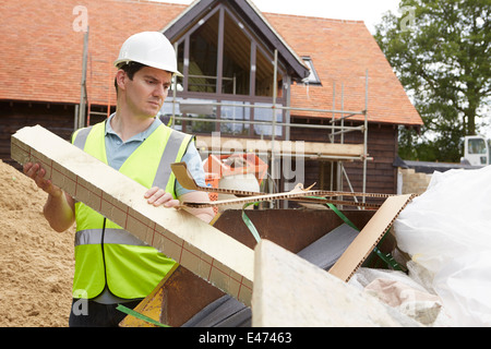 Builder gettare i rifiuti nel saltare sul sito in costruzione Foto Stock