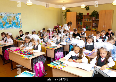 Gli studenti della scuola elementare a banchi e la loro insegnante Foto Stock