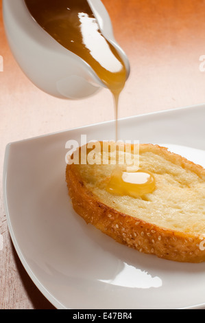 Crostini arrosto al miele pane bianco dolce ad alto contenuto calorico dolce nuova piastra piatto versando bee toast food home nessuno appetitoso gustoso Foto Stock