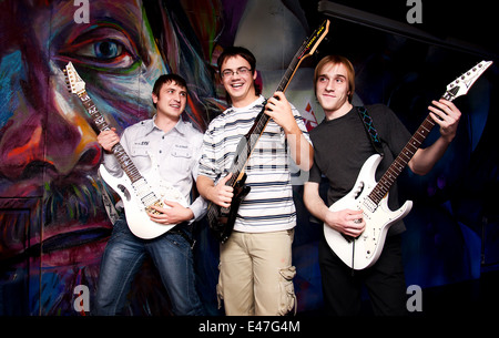 Tre chitarristi rock sono scherzando, sorridendo e riproduzione di musica allegra Foto Stock